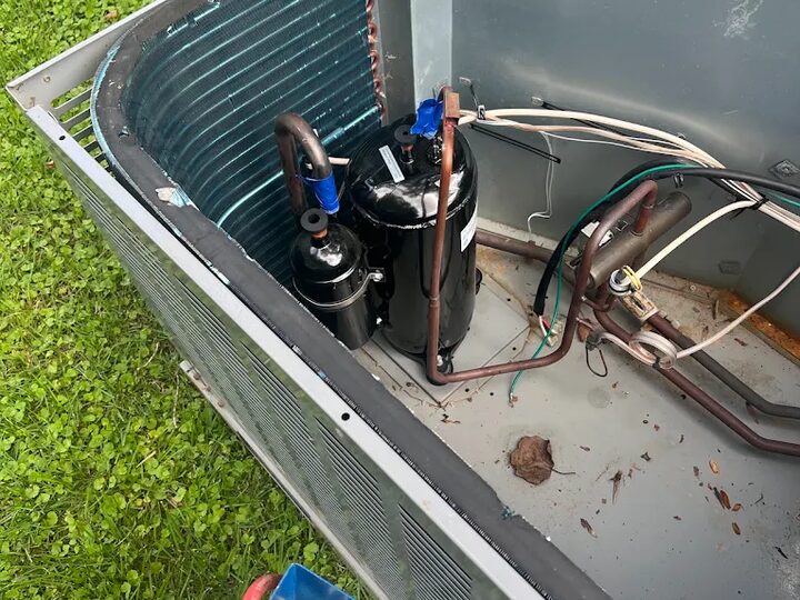A technician reading manifold gauges on a residential condenser unit